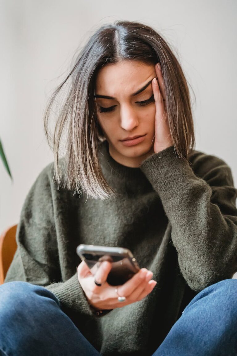 concerned woman browsing smartphone in room