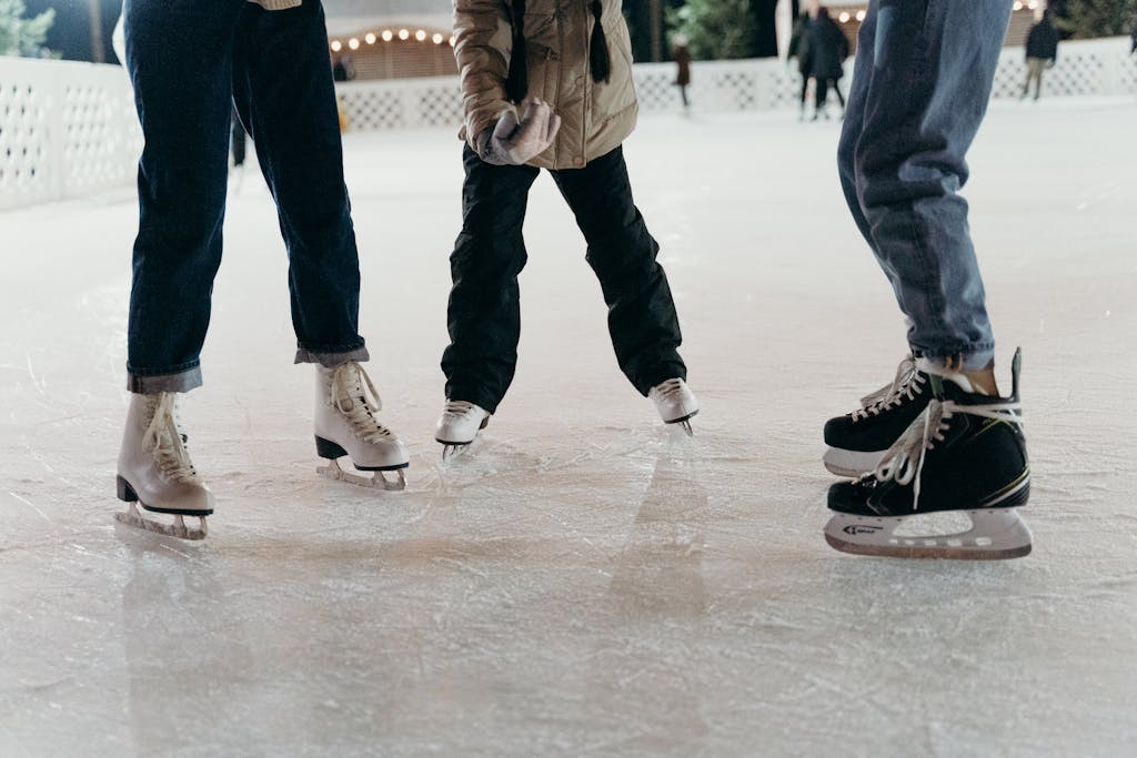 Group of people ice skating on a winter rink, showcasing leisure and enjoyment.