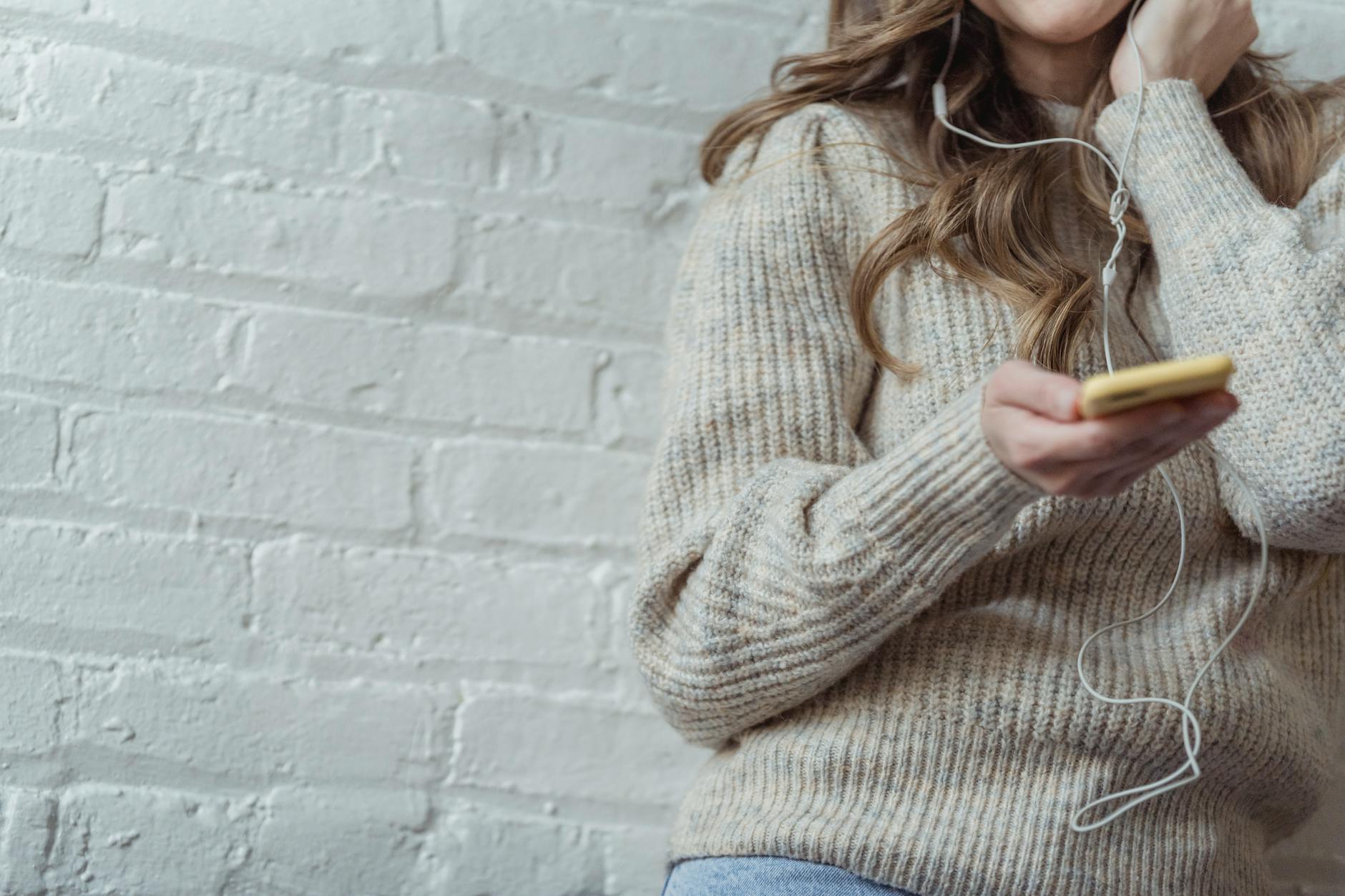 crop lady using smartphone and enjoying music in earphones